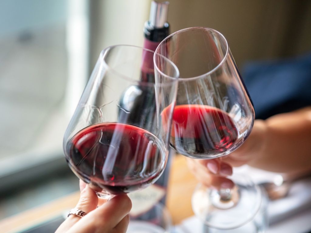 Two hands holding a glass of Malbec vs Cabernet Sauvignon wine