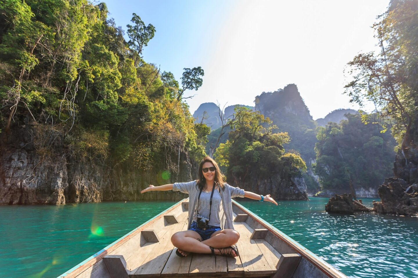 girl on boat traveling with arms spread wide