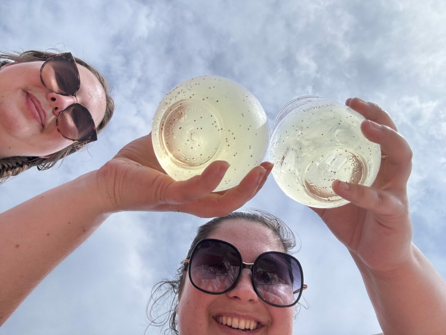 Shot from below of two girls holding stemless wine glasses