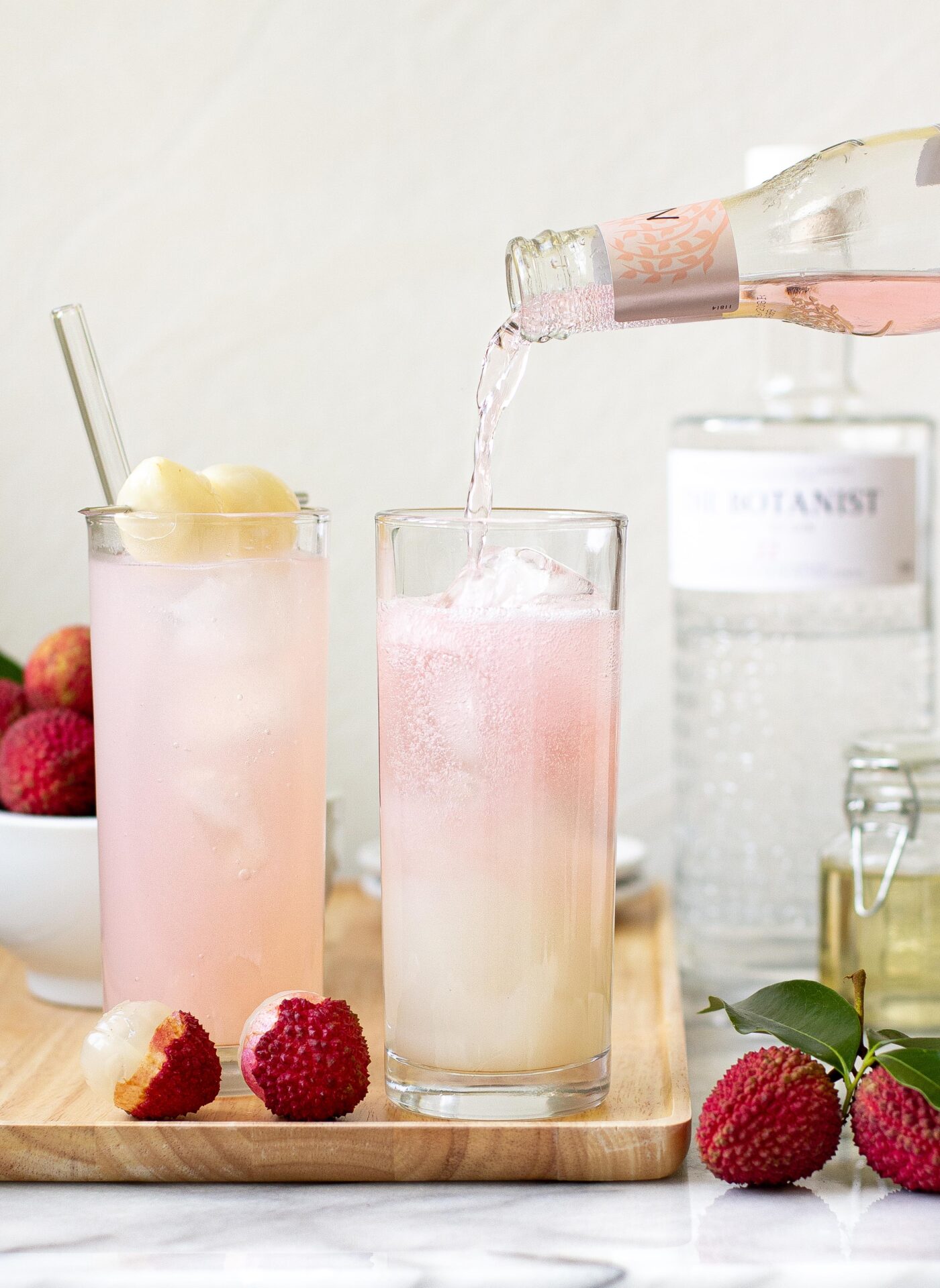 Sparkling Lychee Sweet Cocktails with a drink being poured from a bottle into the long glasses