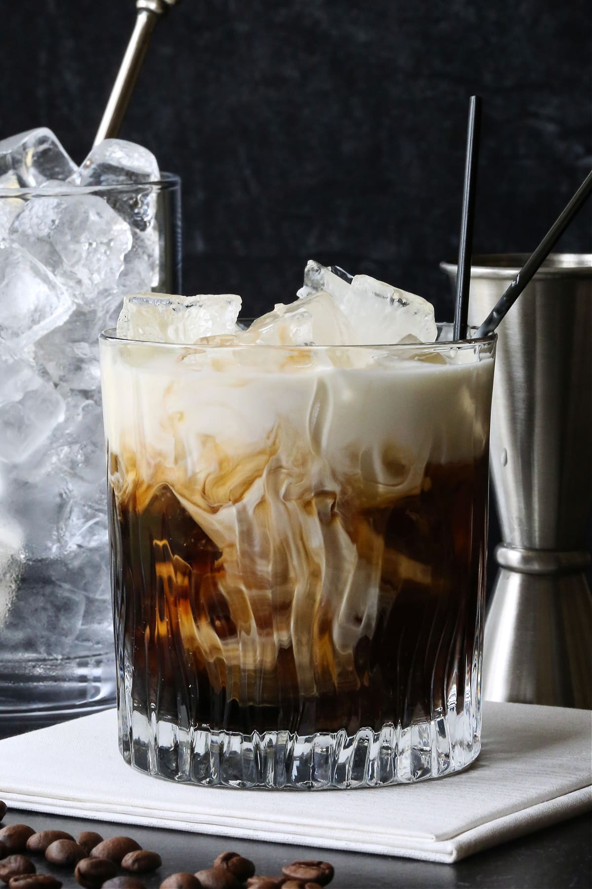 White Russian Sweet Cocktails in a short glass with whipped cream and Ice by the side.