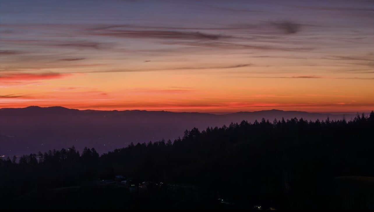 Orange and purple sunset over rolling mountain views