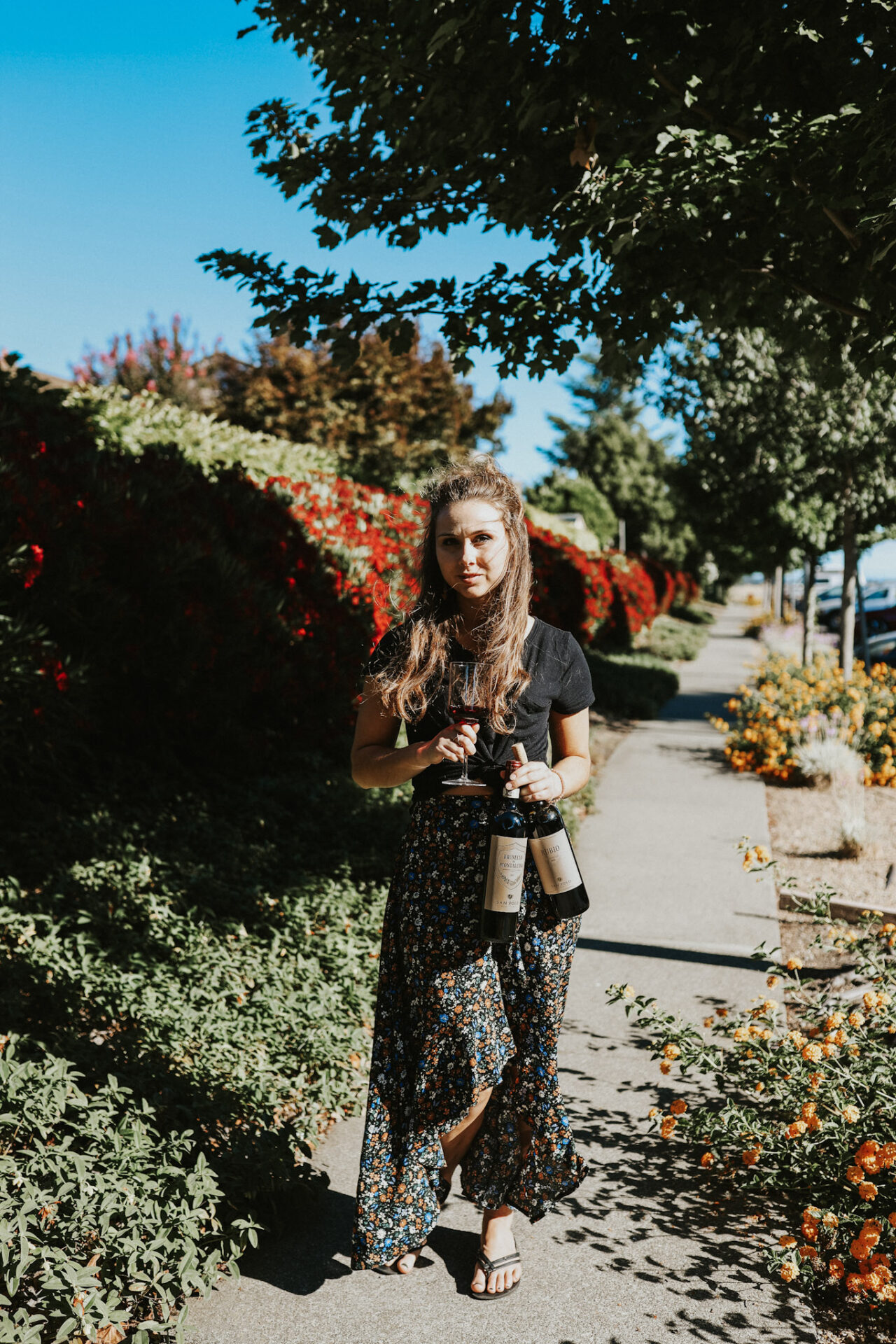 A lady standing and holding Brunello di Montalcino wine bottles