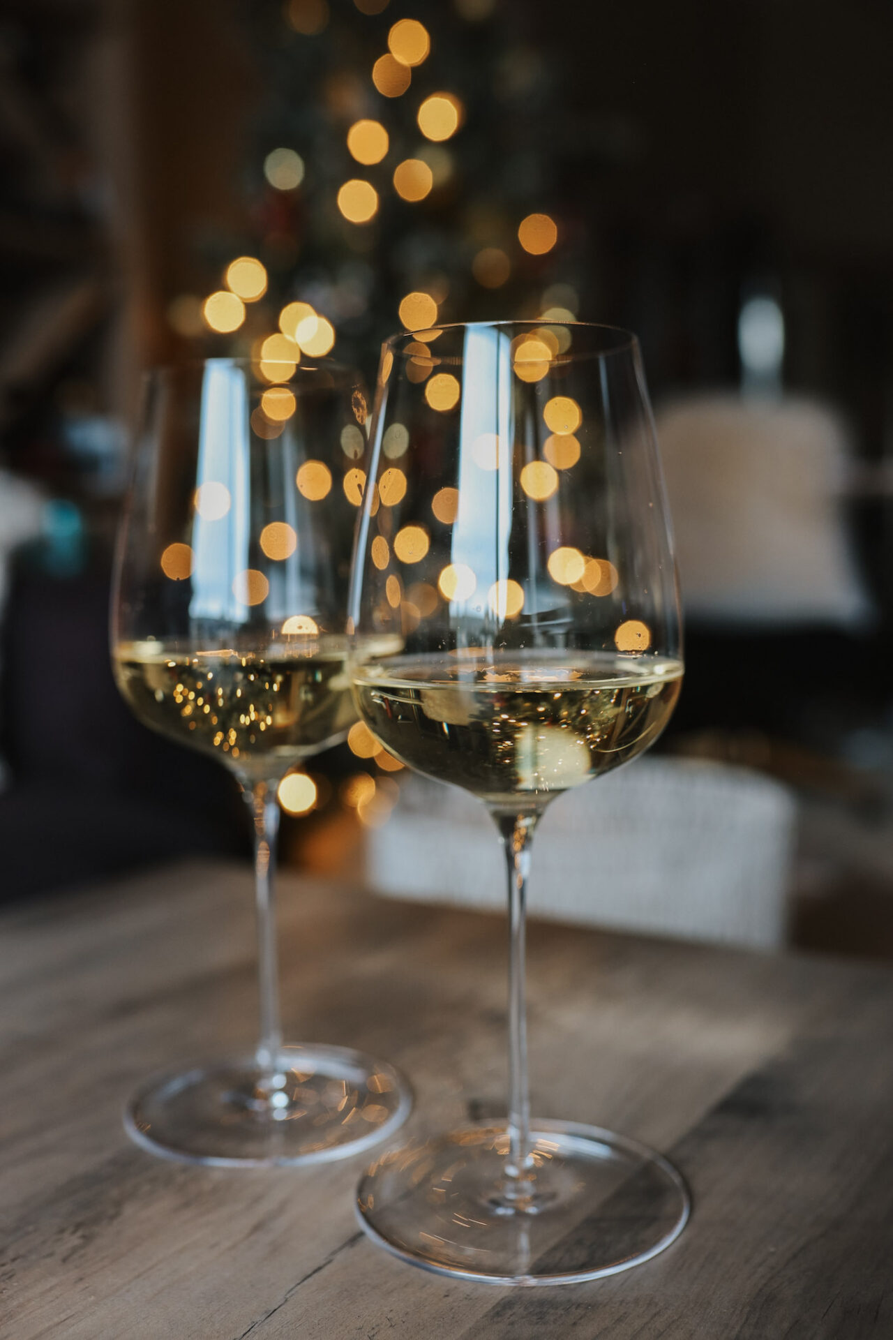 Two GlasVin Universal wine glasses with white wine in them in front of a Christmas tree